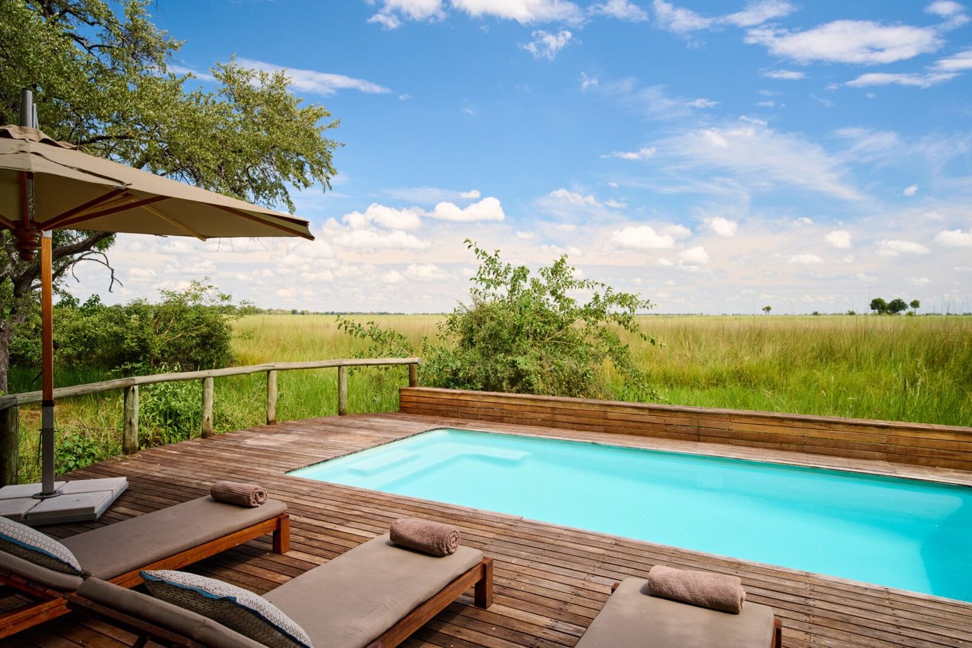 Swimming pool and loungers at Camp Moremi on a deck facing open floodplain grass