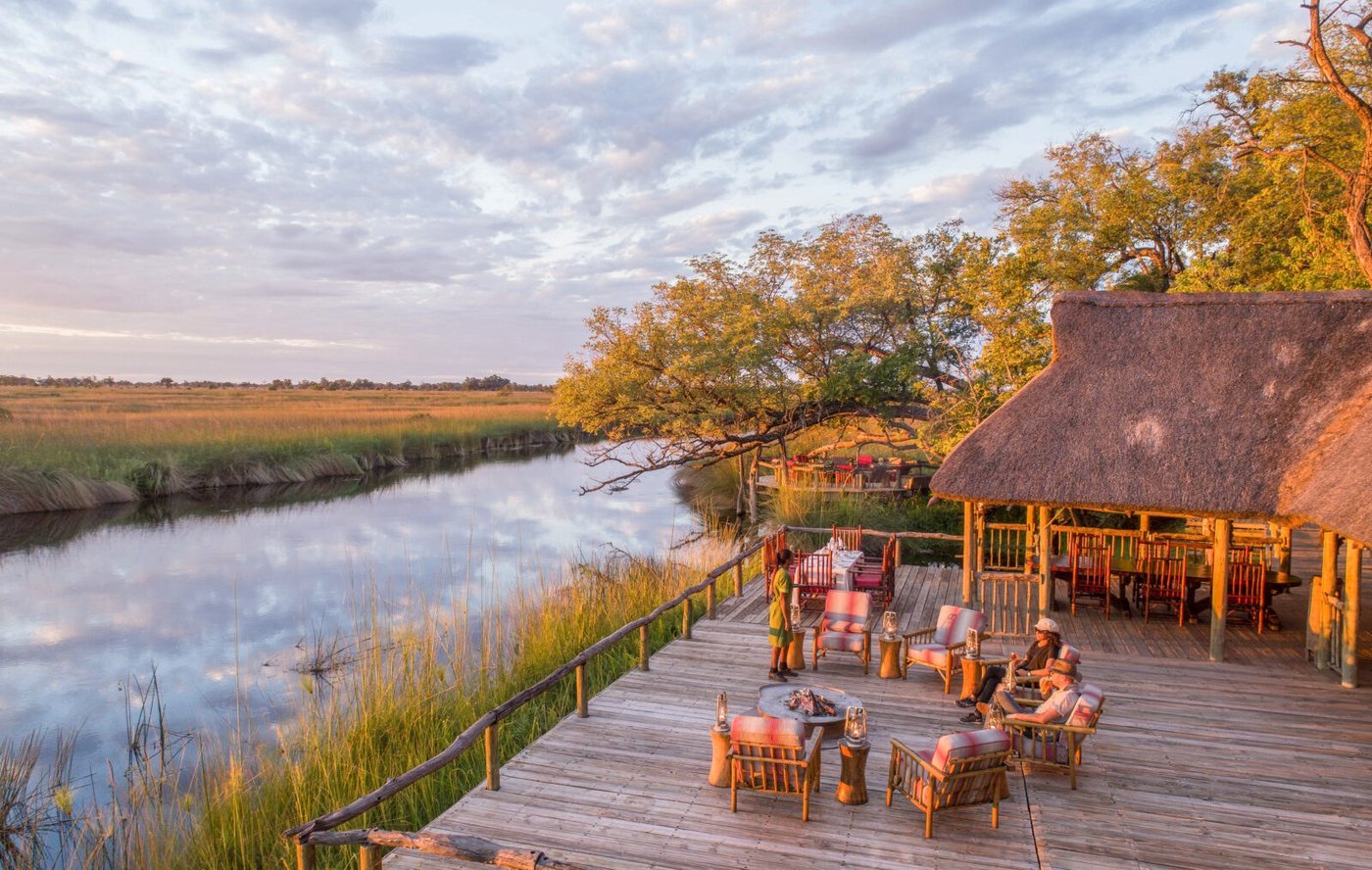 Evening drinks around the fire on the waterside deck at Camp Xakanaxa