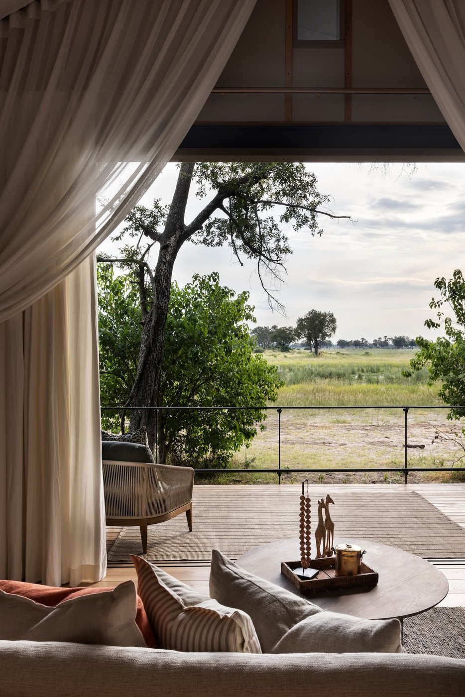 Looking past a sofa and the private deck of a Chitabe Camp suite to open floodplain