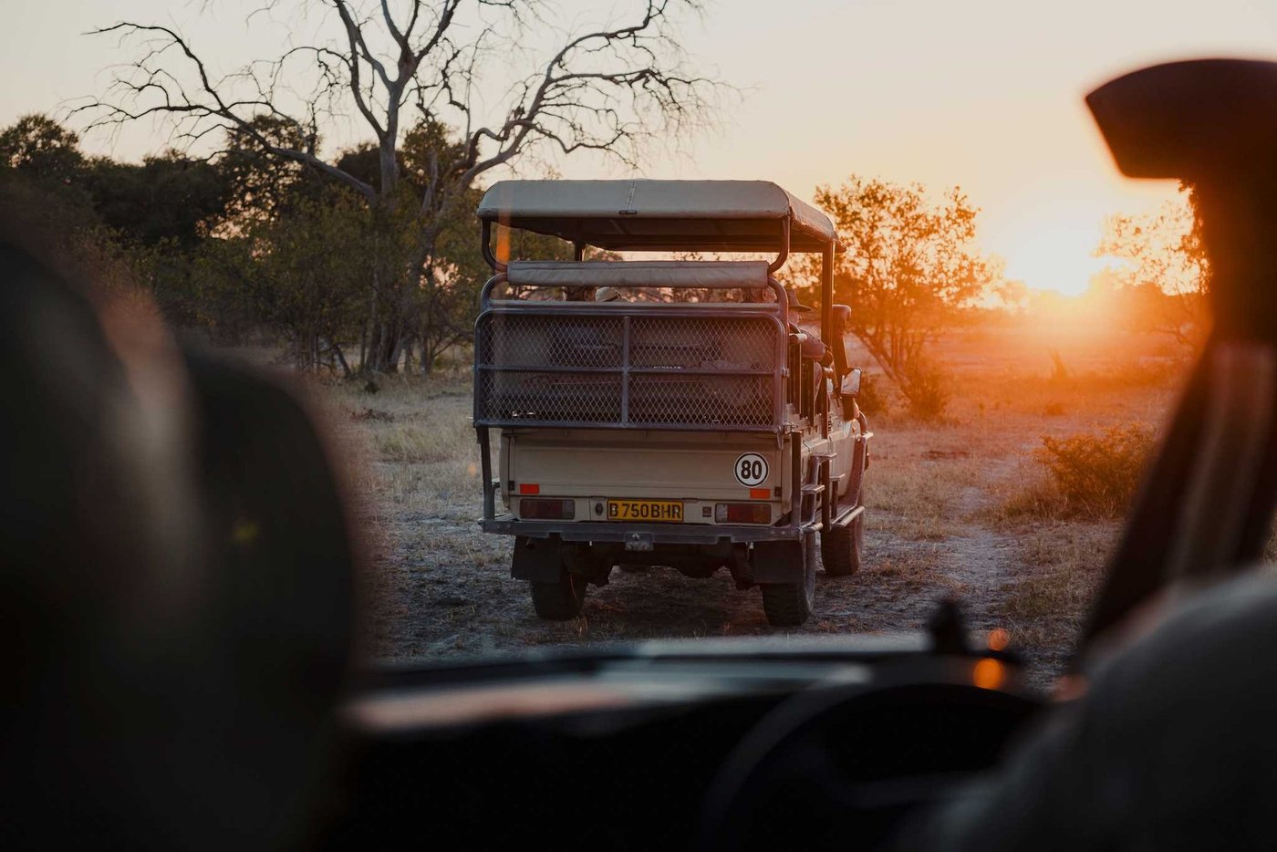 A safari vehicle heads out at sunset from Khwai Leadwood