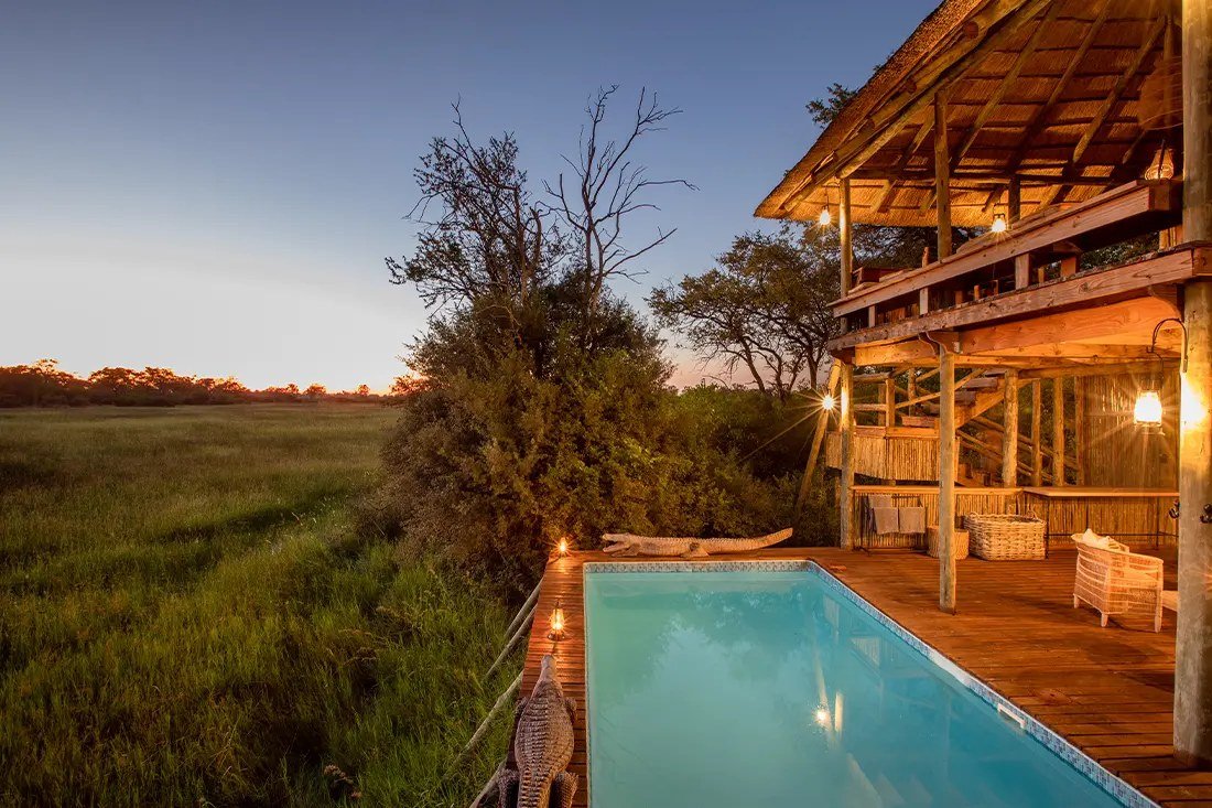 Lantern-lit pool deck at Little Sable looking over grassland as the sun goes down