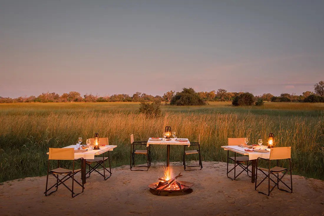 Dinner tables around a fire pit on the sand at Little Sable, facing the floodplain
