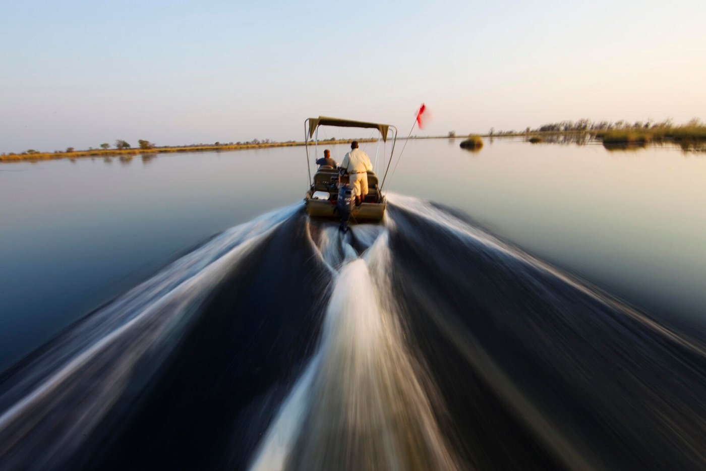 A motorboat speeds across a calm lagoon on a water excursion from Okuti