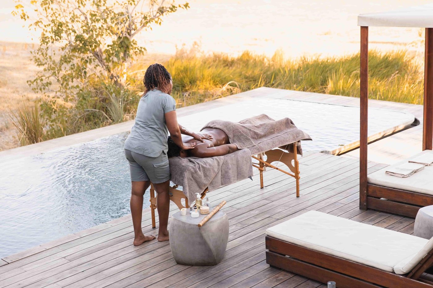 A massage on the pool deck at Qorokwe Camp, with reeds and floodplain behind