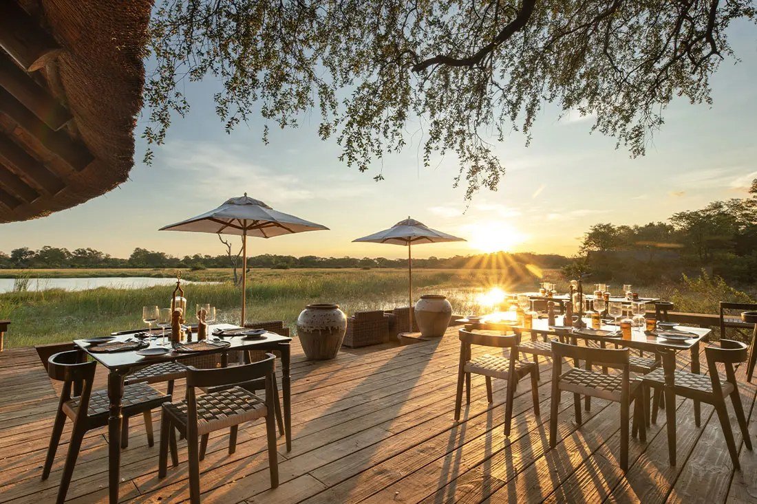 Dining tables laid on the Sable Alley deck as the sun sets over the lagoon