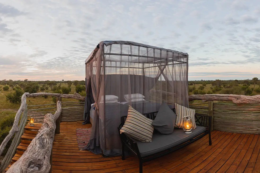Netted bed, cushioned bench and lanterns on the timber top deck at Skybeds