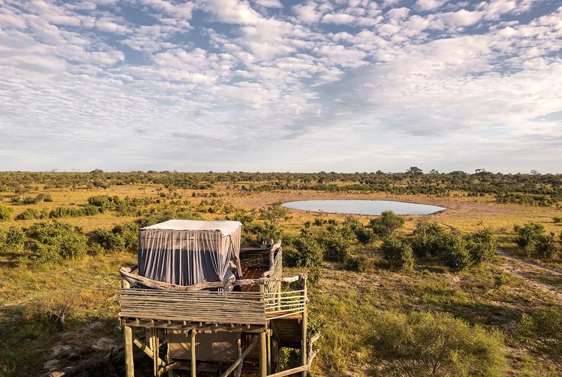 A Skybeds platform stands in open bush with the waterhole a short way beyond