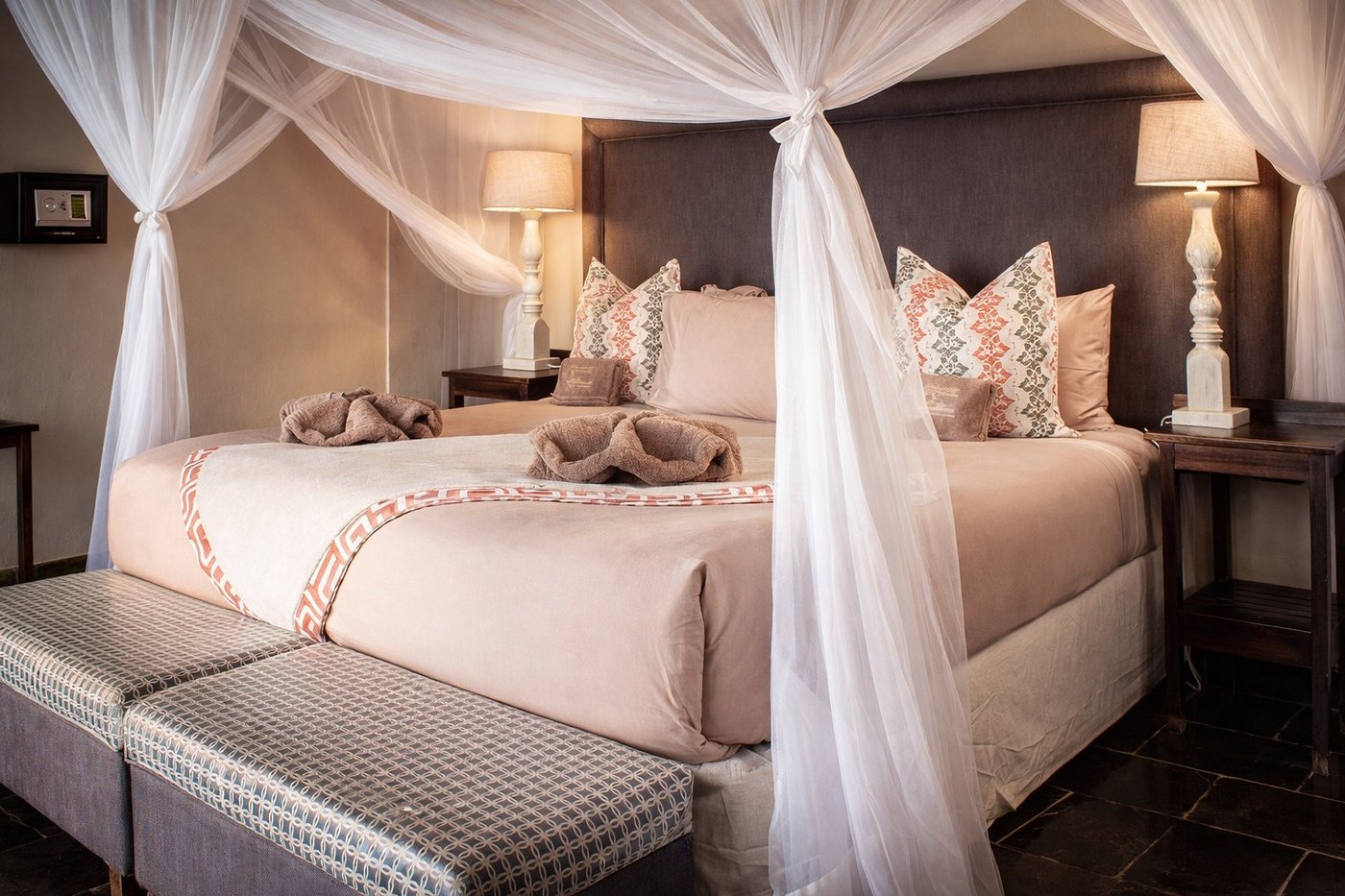 Canopy bed draped in mosquito netting inside a chalet at Thamalakane River Lodge