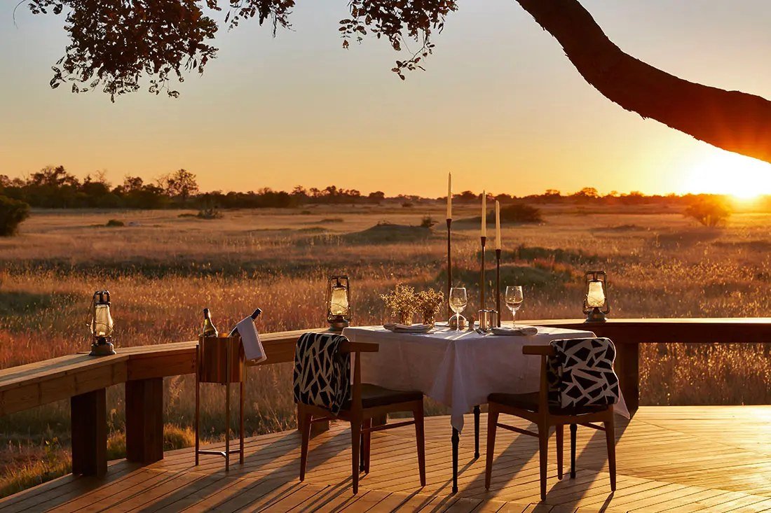 A candlelit table for two on the Tuludi deck, the plains lit by a low sun