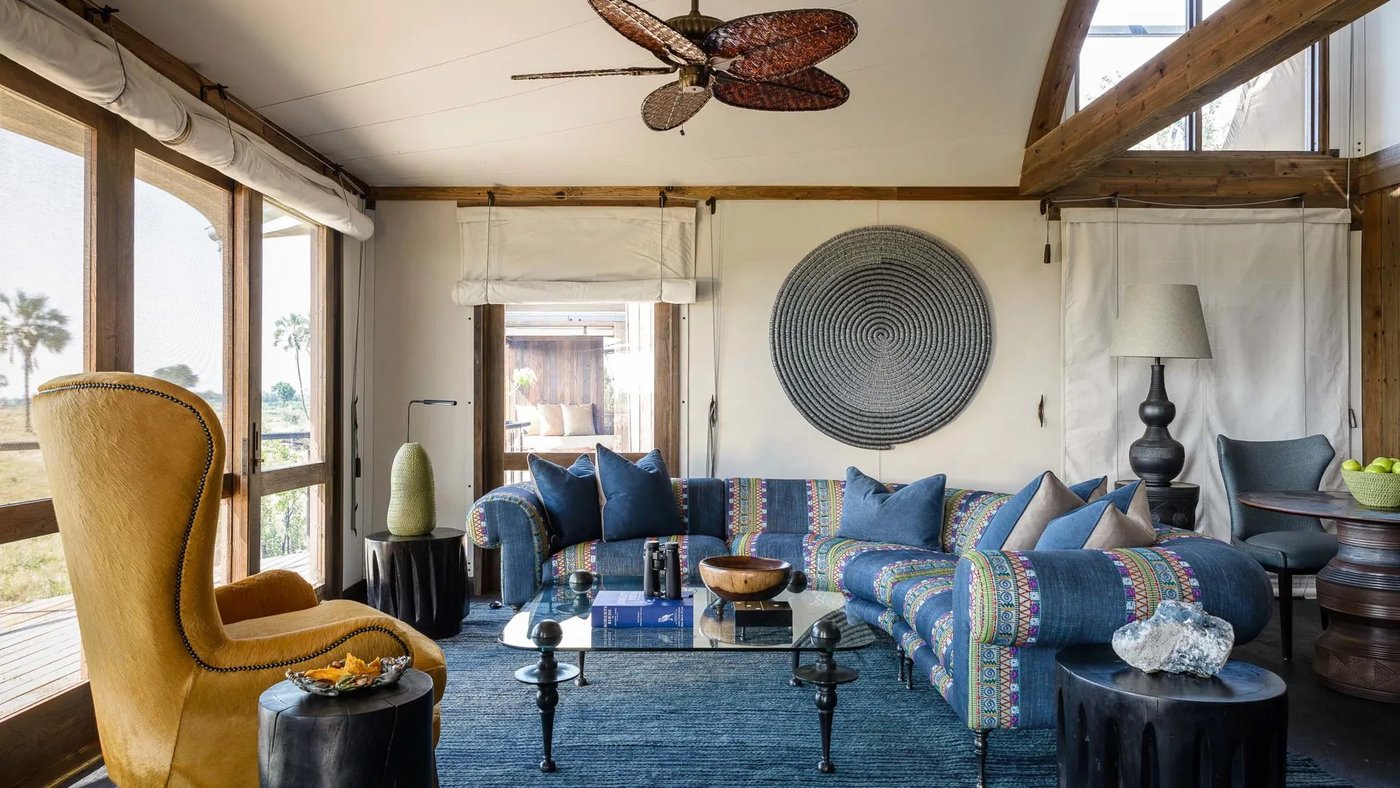 Art-filled lounge with a woven wall hanging and blue sofas at Xigera Safari Lodge