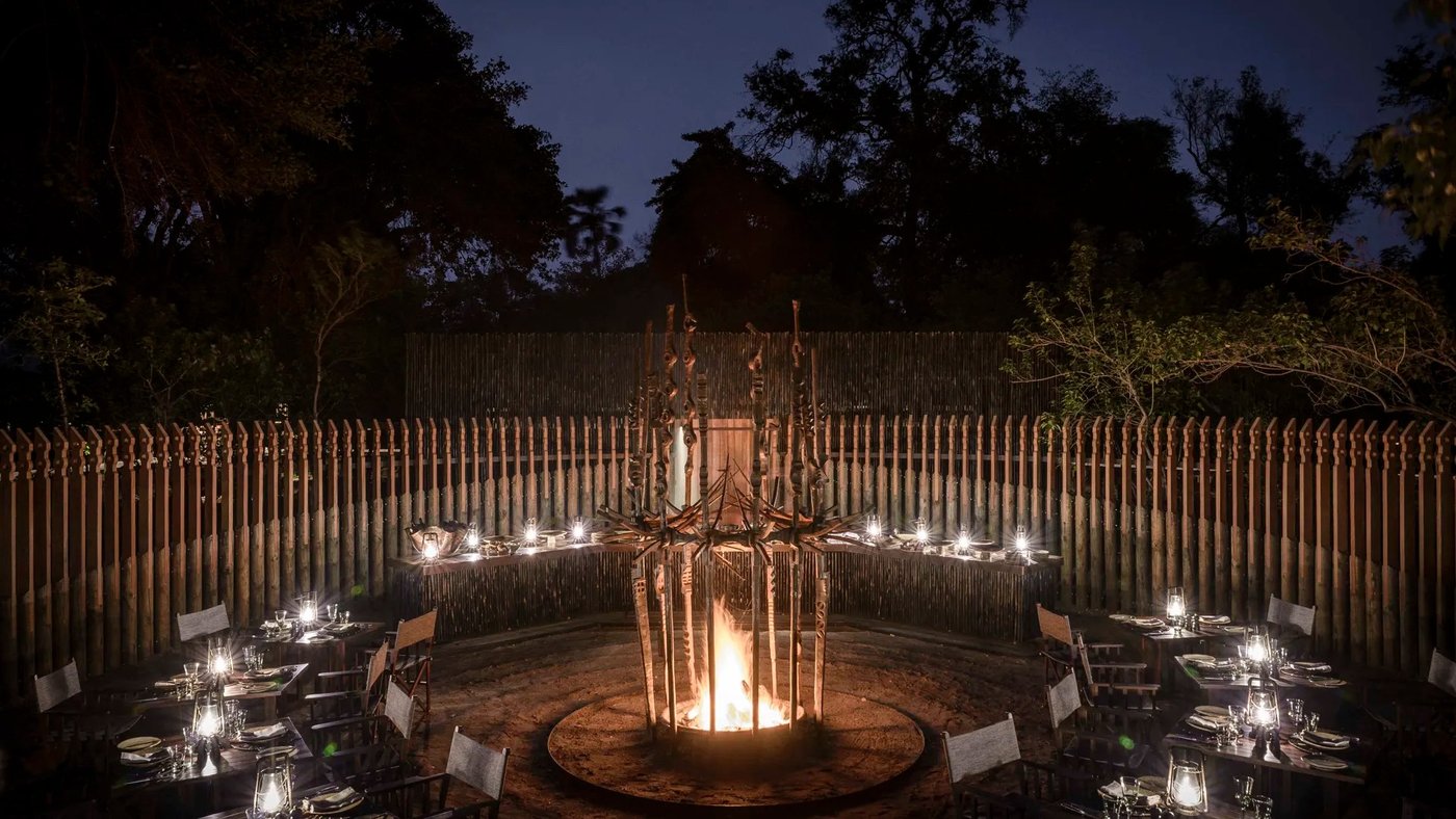Dinner tables lit by lanterns around the boma fire at Xigera Safari Lodge