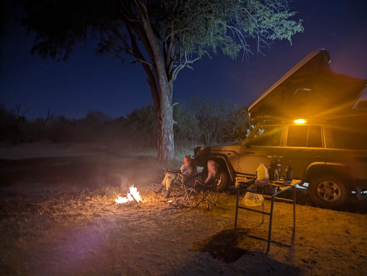 A fire under a big tree, the tent already made up on the roof